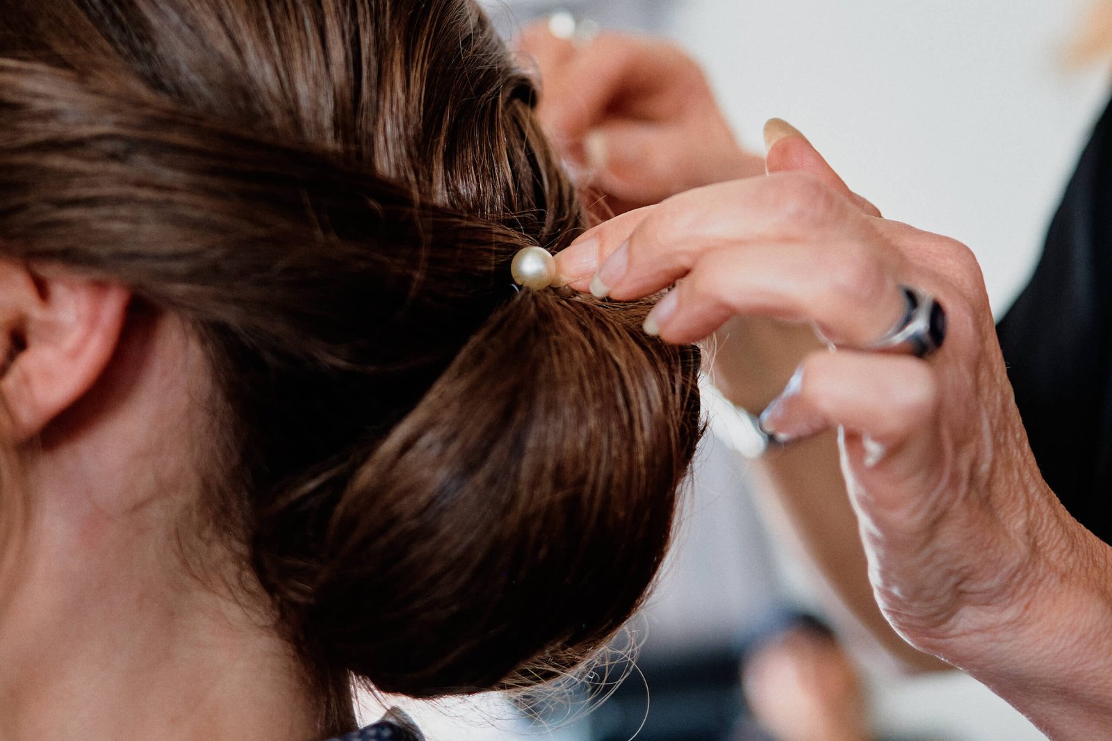 Gros plan sur une épingle à perle de la grand-mère d'Audrey, piquée dans son chignon de mariée